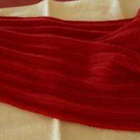 Red Chevron Scarf, sitting folded in half with ends fanned out on white towel on top of red table