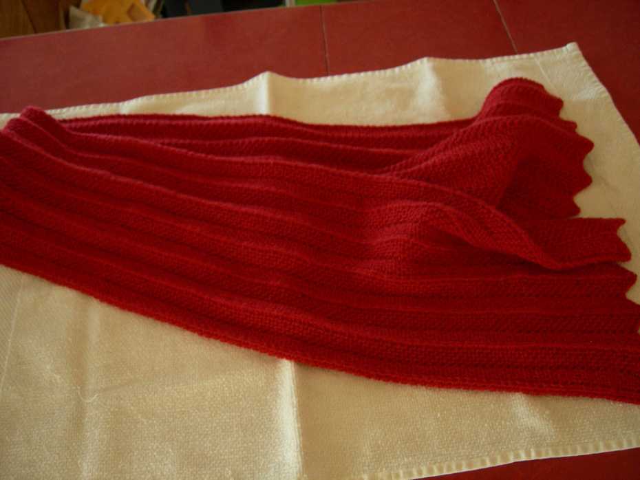 Red Chevron Scarf, sitting folded in half with ends fanned out on white towel on top of red table