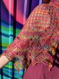 closeup of brightly colored lace shawl showing crochet flower detail, in front of bright graffiti style wall