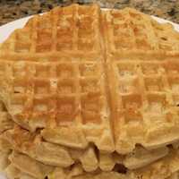 stack of round waffles sitting on a white plate on granite countertop