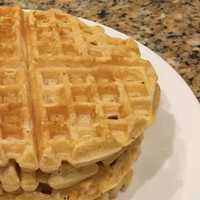 stack of round waffles sitting on a white plate on granite countertop