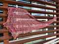 brightly colored elongated diamond shaped shawl, hanging from copper bars to show flat shape