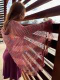 woman peering through slats of copper scaffolding, with broader side of brightly colored shawl towards camera