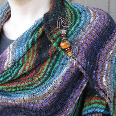 closeup of larger Rosita shawl to illustrate twisted stitch closed lace texture, also features copper shawl pin with large hand-blown glass beads