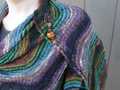closeup of larger Rosita shawl to illustrate twisted stitch closed lace texture, also features copper shawl pin with large hand-blown glass beads