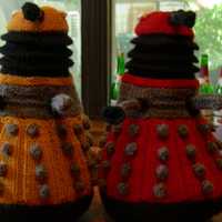 New Paradigm Daleks sitting on table, one orange, one red